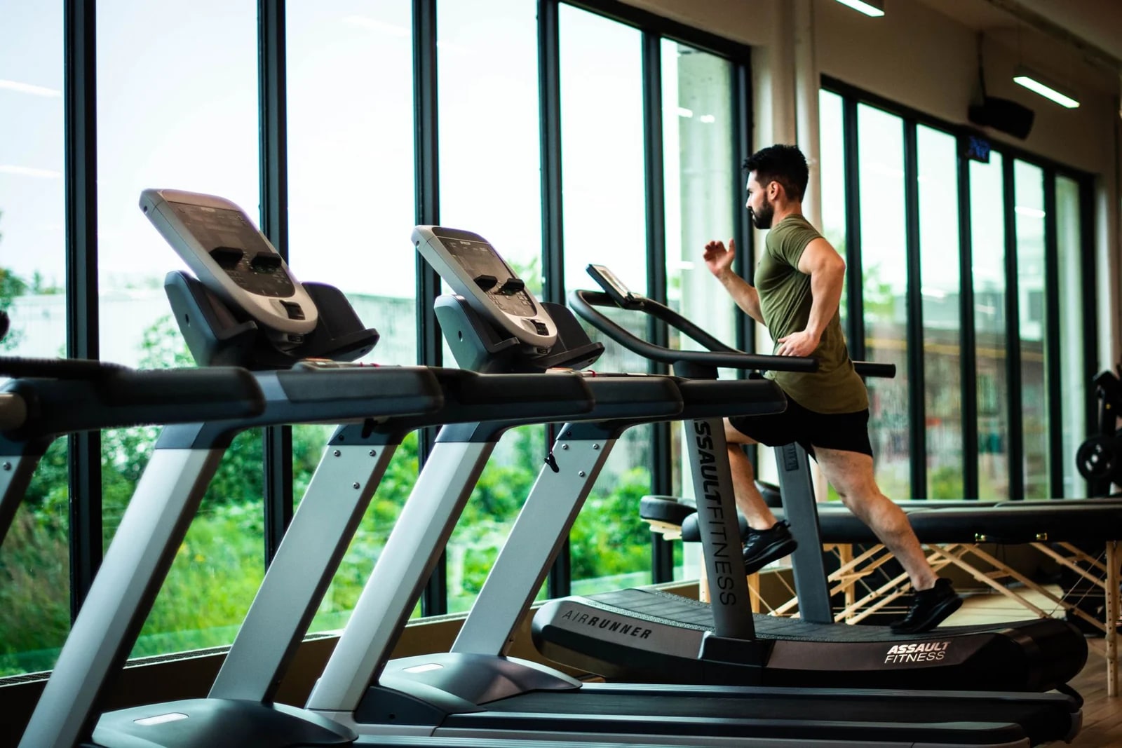 Persona entrenando en el área de caminadoras de un gimnasio
